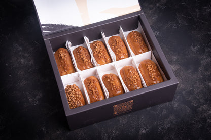 A box of salted caramel mini eclairs, with each piece individually wrapped in white paper and placed in a black box.