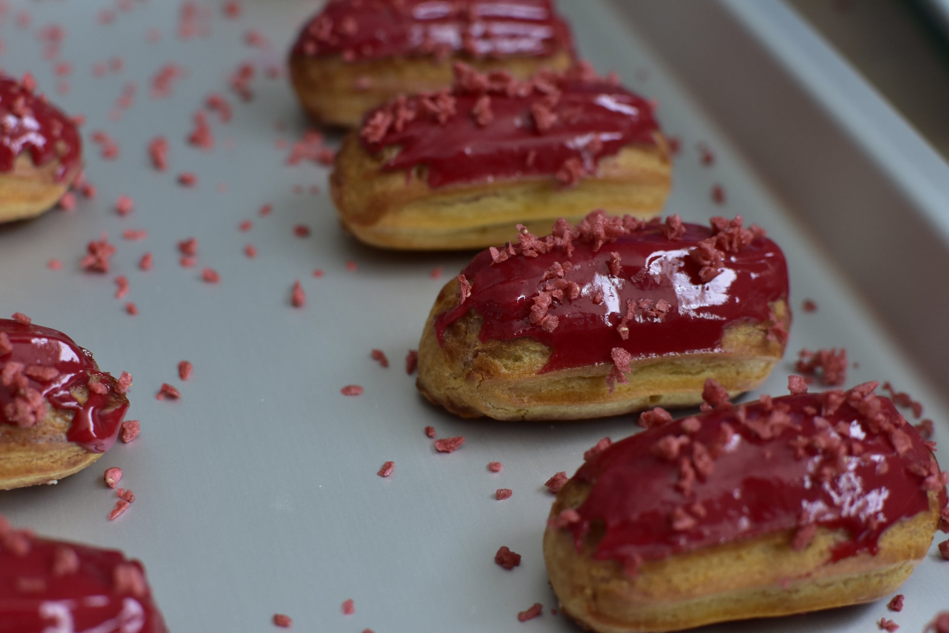 A box of strawberry mini eclairs with glazed strawberry on top, arranged in a decorative box.