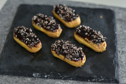 Espresso Mini Éclair on a black square. Coated with espresso and Valrhona Original pure Chocolate.