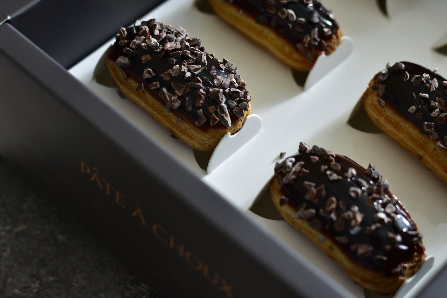 Espresso Mini Éclair in a black box. Coated with espresso and Valrhona Original pure Chocolate.