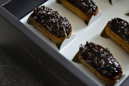 Espresso Mini Éclair in a black box. Coated with espresso and Valrhona Original pure Chocolate.
