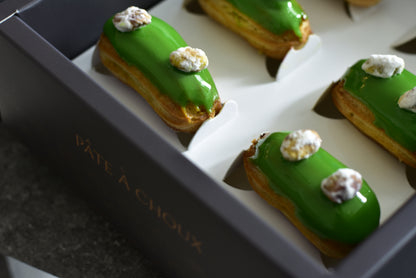A box of Pistachio Mini Eclairs. Spanish pistachios cream, and topped with crystalized sugar coated pistachios. 